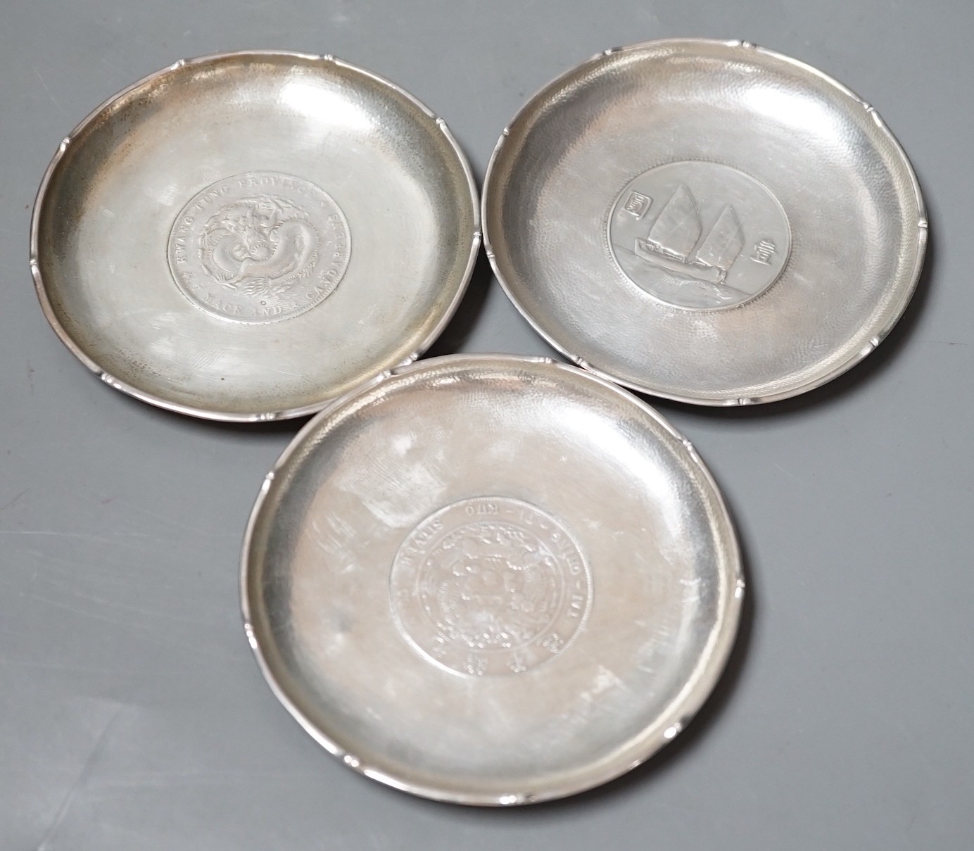 Three Chinese white metal dishes, each inset with coin, maker HC, 94mm, 196 grams gross.